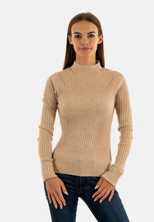 Maglione a collo alto beige a coste, con maniche lunghe, realizzato in tessuto morbido, caratterizzato da una forma aderente e un motivo strutturato. Abbinato a jeans scuri.