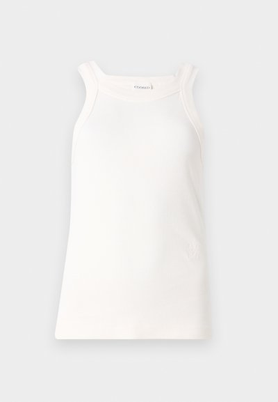 Hvit ribbestrikket tanktopp med rund halslinning og brede stropper. Har en subtil logo detalj på kanten. Myk stoffkvalitet med figurnær passform.