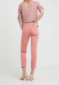 Jeans skinny de mezcla de algodón rosa con una cintura de altura media, que cuentan con un diseño de cinco bolsillos y detalles de costura sutiles. Combinados con tacones bloque nude.