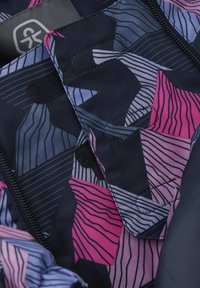 Marinblått tyg med ett geometriskt mönster i rosa, lila och grått. Inkluderar svarta dragkedjor och kardborreknäppningar. Strukturerad yta.