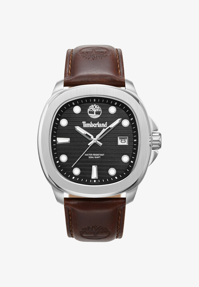 Kwadratowy zegarek ze stali nierdzewnej z czarną teksturowaną tarczą, białymi znacznikami godzin, brązowym skórzanym paskiem i wyświetlaczem daty na pozycji 3. godziny.