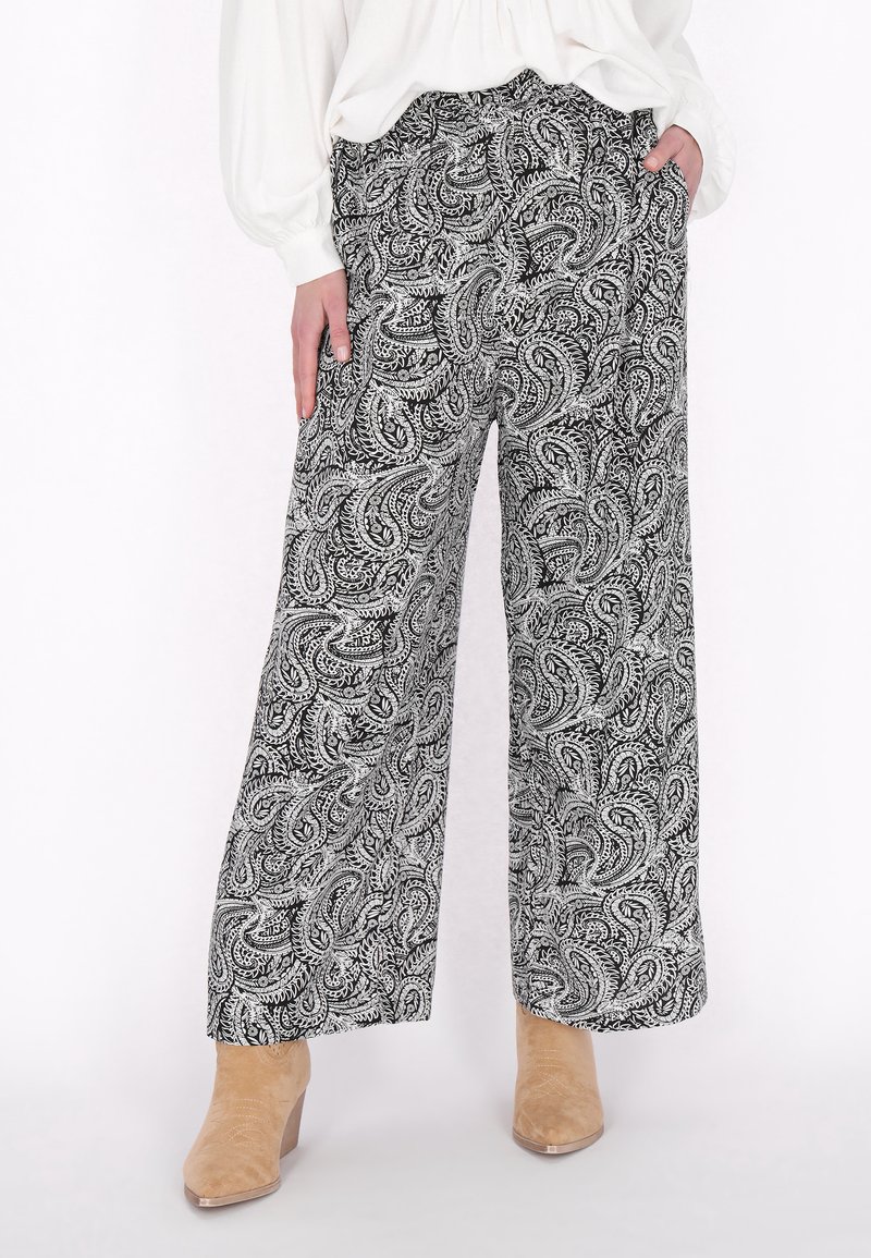 Pantaloni a gamba larga in bianco e nero a motivo paisley, con una texture morbida, dotati di vita alta e tasche laterali, abbinati a stivali alla caviglia beige.