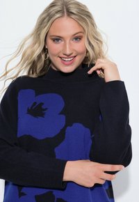 Maglione navy con grande motivo floreale blu, collo alto e maniche lunghe. Texture morbida con accenti a coste al colletto e ai polsini.