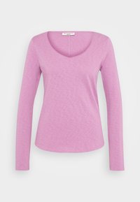 Pitkähihaista puseroa vaaleanpunaisena, jossa on V-kaula-aukko. Valmistettu pehmeästä, teksturoidusta kankaasta, jossa on hieman kaareva helma.