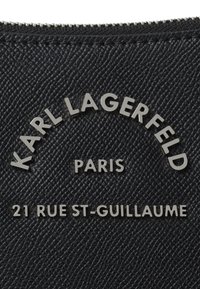 Materiale nero testurizzato con lettering argentato, con "KARL LAGERFELD PARIS" e "21 RUE ST-GUILLAUME" in rilievo. Chiusura con zip.