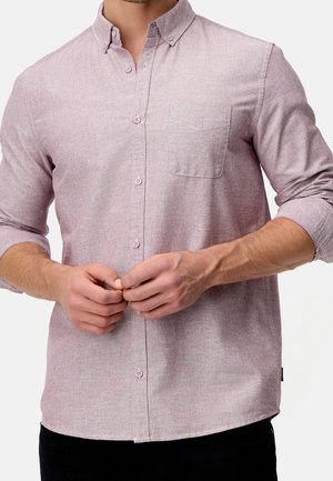 Light purple button-up shirt with a chest pocket, long sleeves, subtle texture, and pink buttons, worn by a person adjusting it.