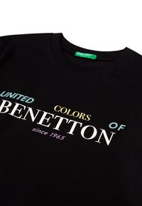 Czarny bawełniany t-shirt z wielokolorowym napisem "United Colors of Benetton since 1965", z okrągłym dekoltem i luźnym fasonem.