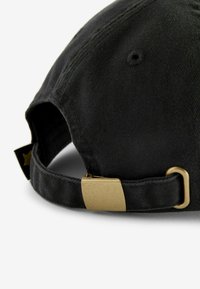 Casquette noire en coton avec une visière incurvée, un tissu texturé, et une boucle en métal doré sur une sangle réglable à l'arrière.