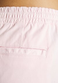 Lichtroze shorts met een elastische tailleband, zachte katoenen stof en een klein achterzakje met een horizontale opening.