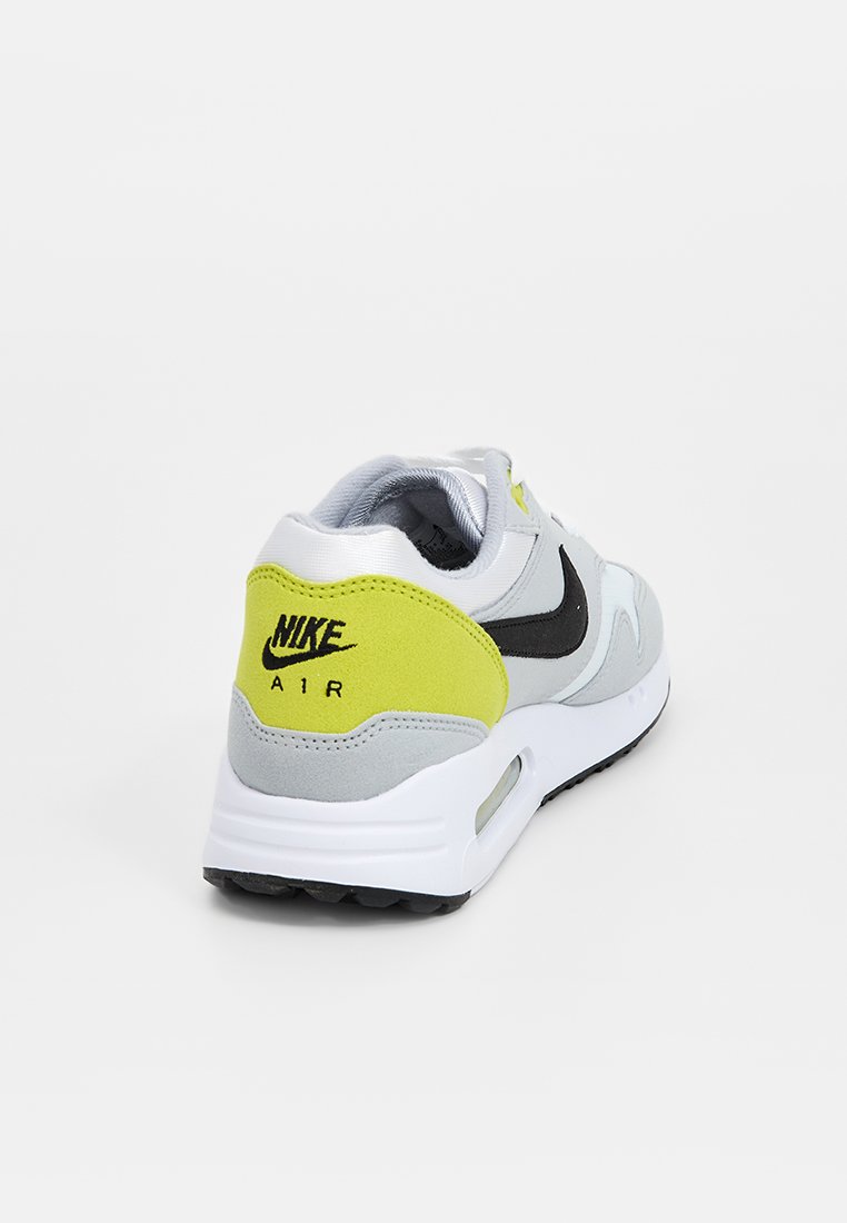 Nike Air sneaker heeft een grijze bovenkant met gele en zwarte accenten, een ronde neus, een gevoerde zool en een zichtbare luchtunit in de hak.