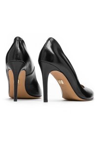 Dei tacchi alti neri in pelle con design a punta, tacco stiletto sottile e un delicato dettaglio di cucitura lungo la cucitura posteriore.