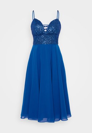 Modré šaty s korálkovou korzetovou částí, hlubokým výstřihem a tenkými ramínky. Volná sukně vyrobená z lehkého materiálu, který dodává jemnou texturu.