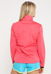 Fitted pink athletic jacket with a high collar, sleek design, and reflective accents. Smooth fabric and seamless stitching.