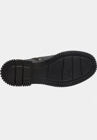 Suela de bota de goma negra con un patrón texturizado y estriado y profundos surcos para tracción. Bordes reforzados y una superficie central lisa.