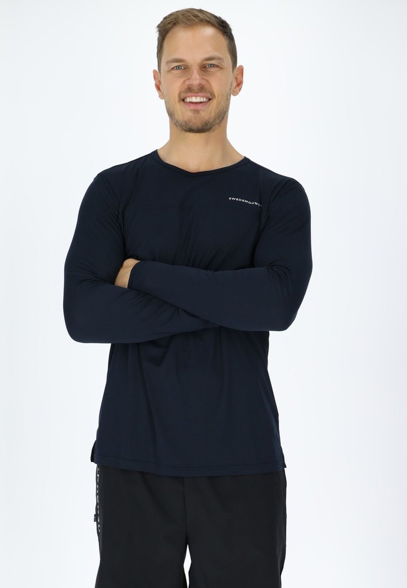 Men's long-sleeve shirt in navy, made from lightweight fabric. Features a round neckline and a subtle logo on the chest. Smooth texture.