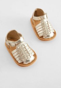 Goldene Leder-Sandalen mit geflochtenem Riemendesign, offenem Zeh, verstellbarem Knöchelriemen und flacher, bräunlicher Sohle, geeignet für Kinder.