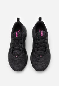 Zapatillas deportivas negras con una parte superior de malla texturizada, cordones negros, un logotipo rosa en la lengüeta y el costado, y un diseño elegante.