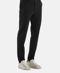 Pantaloni neri slim fit, con tasche laterali, frontale piatto e una texture liscia. Abbinati a sneakers beige.