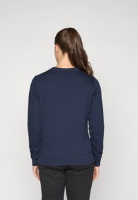 Sweat-shirt bleu marine avec des manches longues, poignets et ourlet côtelés, texture lisse, design simple et col rond ; vu de dos.