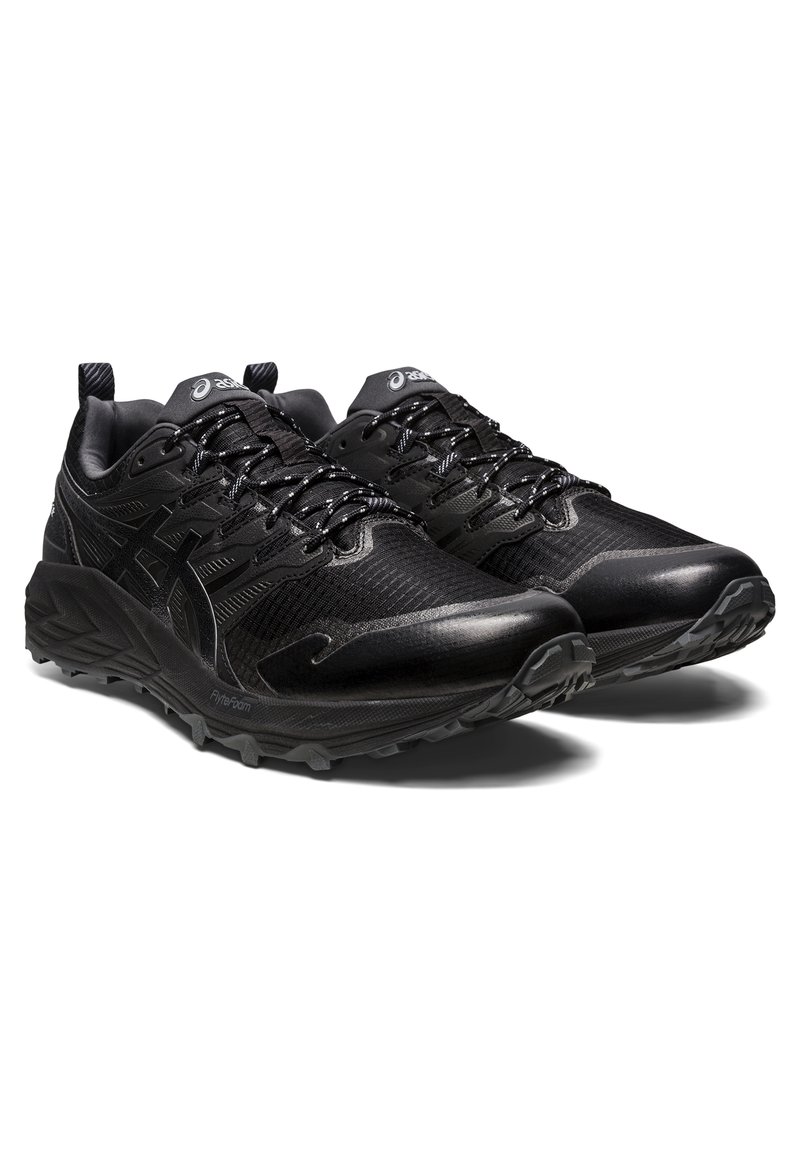 Zapatillas deportivas negras con una parte superior texturizada, acentos reflectantes y una suela de goma robusta. Presentan cordones y un cuello acolchado para mayor comodidad.