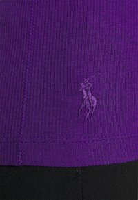 Purple ribbed fabric t-shirt featuring a small embroidered logo of a horse and rider. The texture is smooth, with a fitted cut.