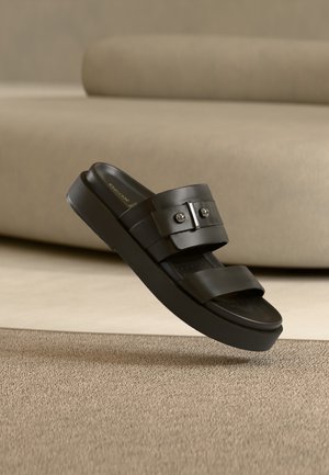 Sandalia negra de plataforma con dos tiras anchas con acentos metálicos, textura suave y plantilla contorneada.