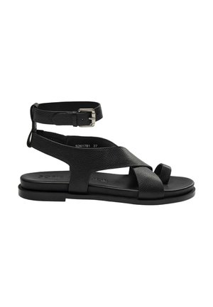 Sandale plate en cuir noir avec bride de cheville à boucle, brides croisées à l'avant et boucle pour l'orteil sur semelle plate.