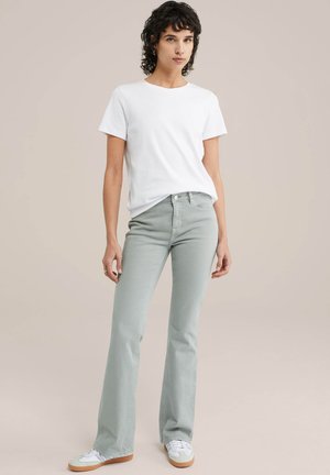 Lichtgroene uitlopende jeans met een aansluitende taille, gecombineerd met een eenvoudige witte t-shirt met korte mouwen en witte sneakers. Zorgvuldig afgewerkt stof.
