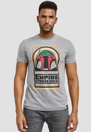 Harmaa puuvillapaita, jossa on graafinen painatus kypärästä ja teksti "The Empire Strikes Back". Pyöreä kaula-aukko, lyhyet hihat ja rento malli.