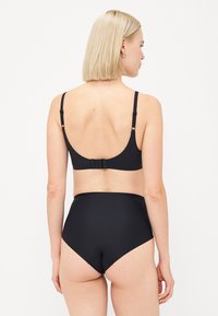 Svart bikini-sett laget av en glatt, elastisk stoff. Toppen har justerbare stropper og en baklås; det høyhåndte bunnen gir full dekning.
