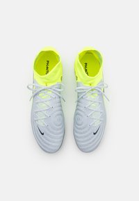 Scarpette da calcio grigio chiaro con tomaia testurizzata, colletto giallo neon e logo Nike nero. Presentano lacci e motivi disposti strategicamente.