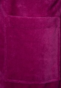 Fuchsia plush fabric with a soft texture, featuring a single rectangular patch pocket. The background is a slightly darker shade.