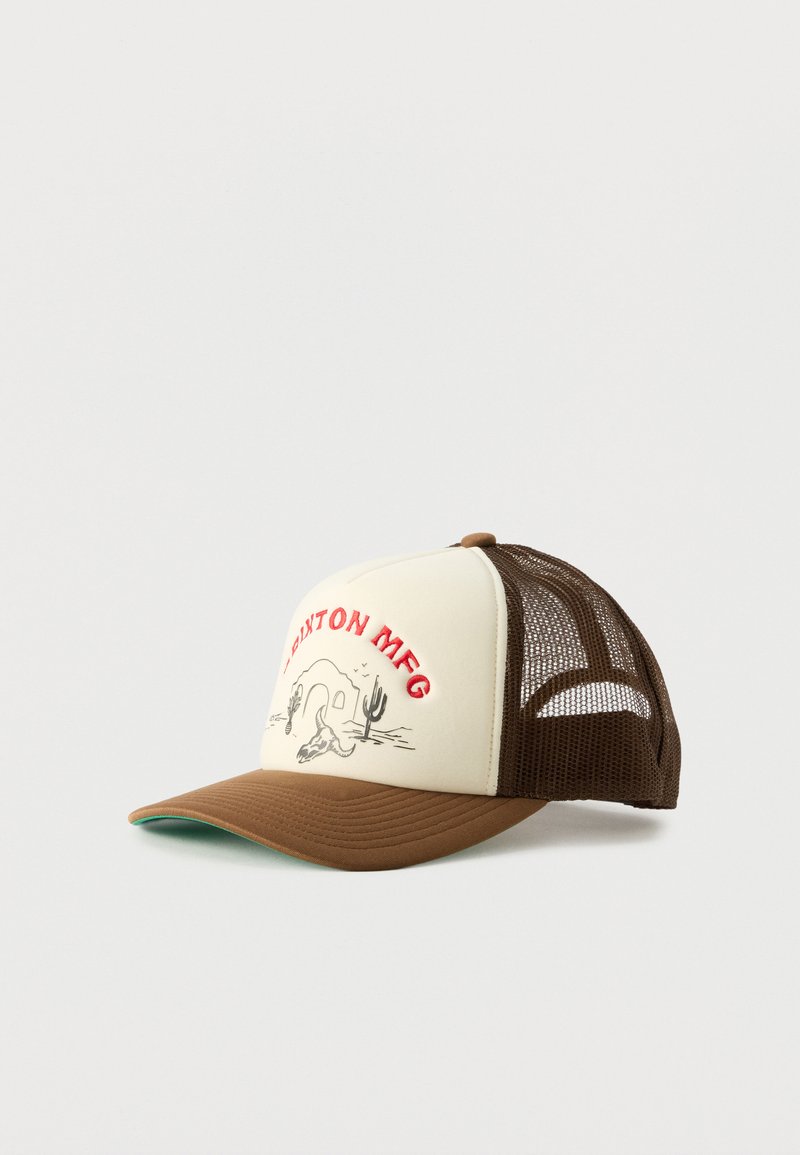 Casquette trucker marron et crème avec arrière en mesh, texte rouge brodé « BRIXTON MFG », et scène désertique avec cactus et crâne sur le panneau avant.