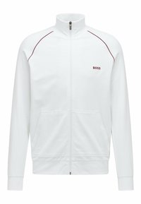 Giacca bianca con zip, realizzata in tessuto morbido, dotata di collo alto, tasche laterali, dettagli rossi sulle spalle e logo "BOSS" ricamato.