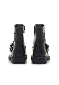 Botas negras hasta el tobillo con un exterior de cuero suave, paneles laterales de feltro, hebillas decorativas y suelas de goma texturizada.