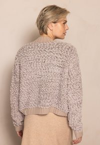 Hellbeiger, strukturierter Pullover mit kurzem Schnitt, gerippten Bündchen und Kragen, mit einer flauschigen Oberfläche und weichem Strickmaterial.