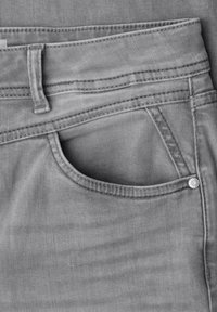 Gros plan d'un jean en denim gris montrant la ceinture, la boucle de ceinture, la poche et le détail de rivet métallique.