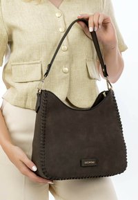 Brown suede handbag with stitched detailing and a single shoulder strap. Features a gold hardware logo plate at the front.