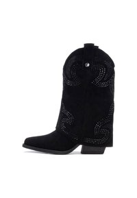 Botas de vaquero de ante negro con punta cuadrada, decoradas con remaches metálicos en un patrón en espiral y un tacón bajo.