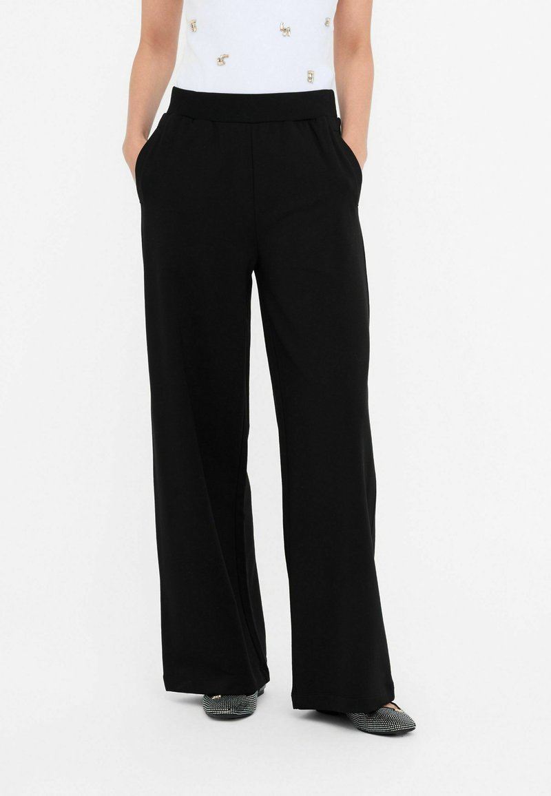 Pantaloni negri cu croi larg, prevăzuți cu un elastic în talie, având buzunare laterale și o textură netedă, moale. Potriviți atât pentru îmbrăcăminte casual, cât și pentru ocazii formale.