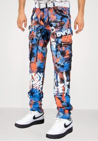 Cargohosen mit einem mehrfarbigen abstrakten Muster in Blau, Orange und Schwarz. Hergestellt aus strapazierfähigem Stoff mit mehreren Reißverschluss-Taschen.