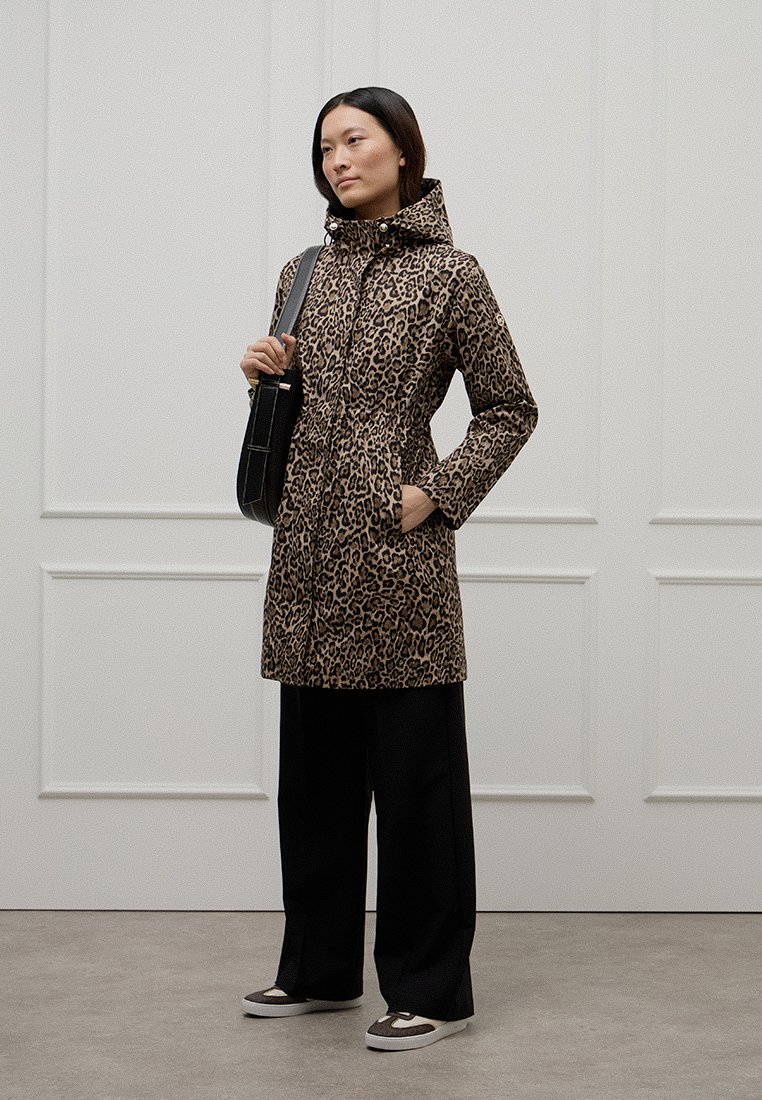 Manteau en imprimé léopard avec capuche, fermeture éclair à l'avant et taille élastique, associé à un pantalon large noir et des baskets.