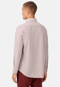 Camicia a maniche lunghe di un rosa pallido con righe verticali, colletto a punta e polsini con doppio bottone. Tessuto di cotone liscio con una vestibilità sartoriale.