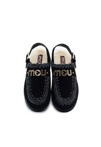 Zoccoli neri in suede con una morbida fodera bianca, cuciture decorative grigie e un accento in metallo dorato con logo sul davanti. Design aperto sul retro.