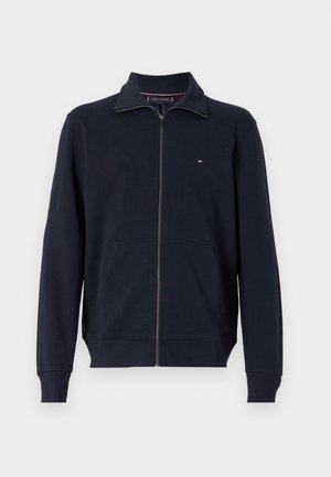 Navy blue zip-up sweatshirt, made of cotton blend. Features a tall collar, two front pockets, and a small logo on the left chest.