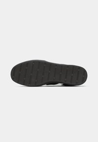 Black rubber shoe sole with horizontal grooves and repeated "JACK & JONES" text pattern, shown against a white background.