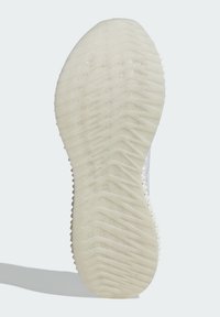 Sole of a shoe, featuring a light beige color, textured surface, and zigzag pattern for traction. Slightly raised edges with a smooth finish.