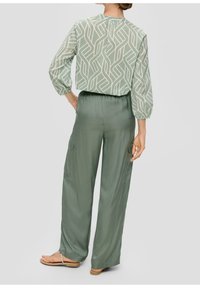 Ljusgrön blus med vitt geometriskt mönster, matchad med löst sittande byxor. Flödande tyg med elastisk midja och sidofickor.