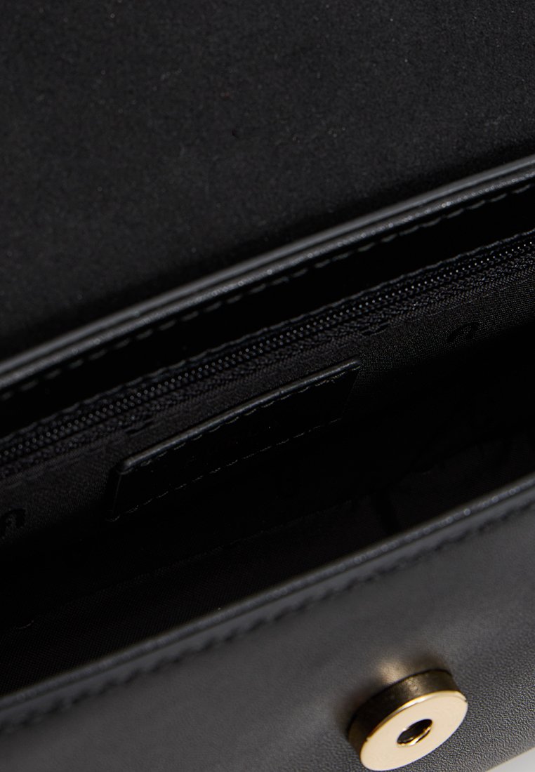 Vista interna di una borsa nera in pelle con una tasca con zip, scomparti piatti e una chiusura a scatto magnetico. Fodera in tessuto texture.