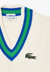 Cream-colored cable knit sweater with a V-neck and blue and green striped accents. Features an embroidered green crocodile logo.